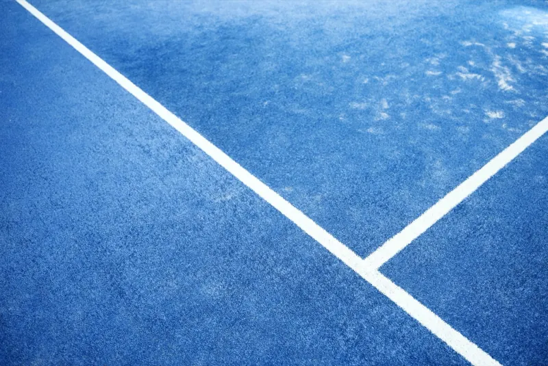White court lines crossing the blue artificial turf of a padel court